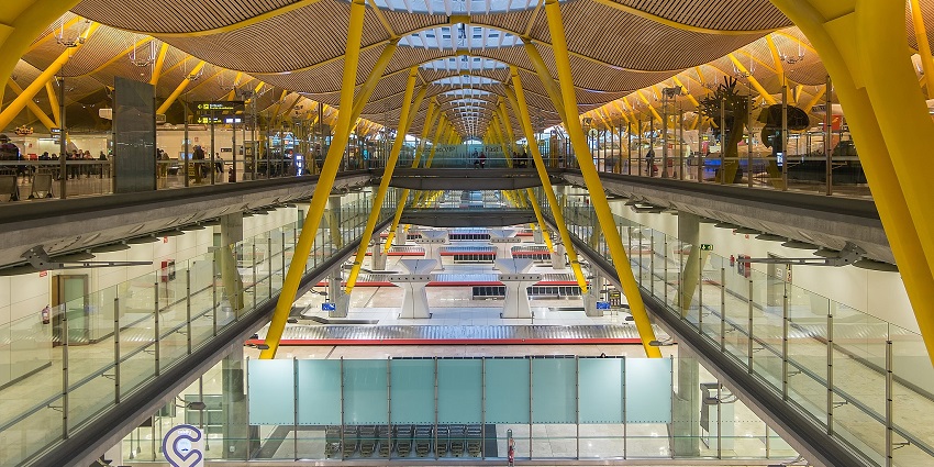 View inside an airport that is decorated with colourful glass sheets with a circular structure above.