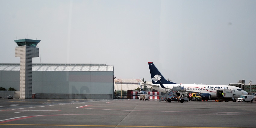 Aeroplane parked at terminal one in Mexico City International Airport and an airport tower