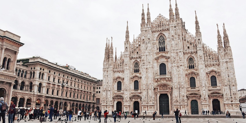 Tourists flock to the historic structure of Milan Cathedral on a sunny day in the city.