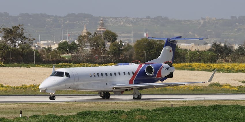 Aeroplane getting ready to take off from the runway with multiple signages and buildings
