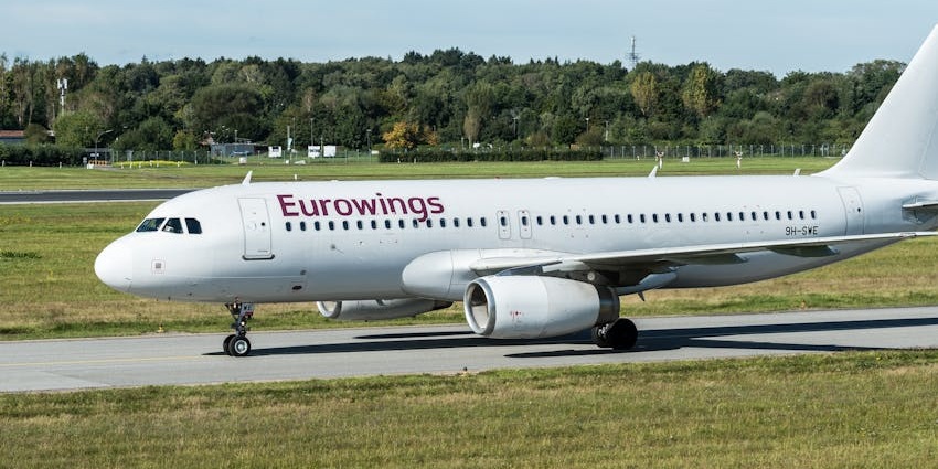 White commercial aeroplane on the runway of the airport with green trees in the background