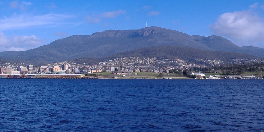Distant view of the Mount Wellington in the background with a marina filled with boats in the forefront.