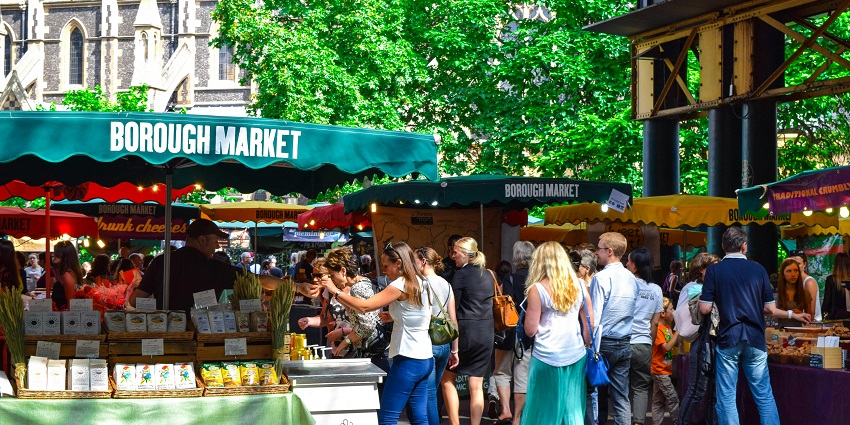 A person handing fresh fruit to another in a crowded farmers market near Mountain View.