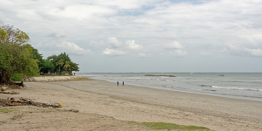 A peaceful view of Muara Beting Beach, with gentle waves lapping the sandy shore under a bright midday sky, one of the best places to visit in Bekasi.