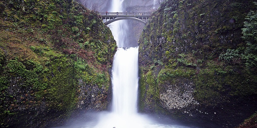 A breathtaking two-tiered waterfall in Oregon, surrounded by lush forests and a scenic bridge.