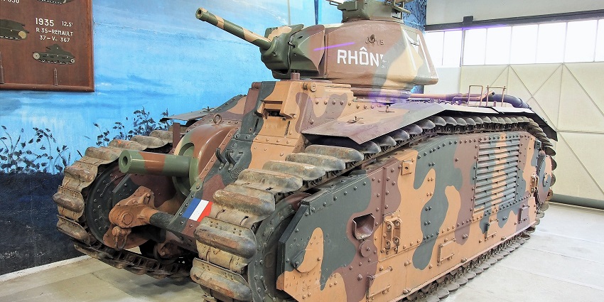 A tranquil tank resting by the serene lush green trees under the clear blue sky.