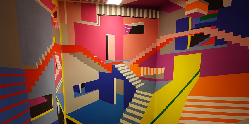An image of the Museum of Illusions Toronto room, with geometric patterns, perspective illusions, and visitors exploring.