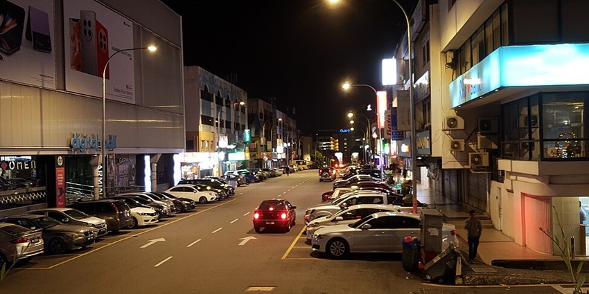 An image of a commercial area in Petaling Jaya at night, featuring cars and Samsung advertisements