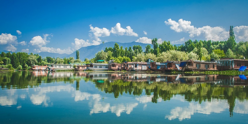Lake with a still water body, multiple houseboats near the lake and distant buildings.