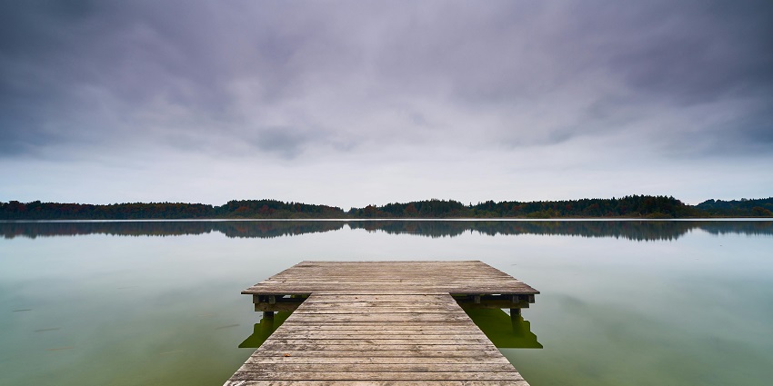 Wooden dock stretches over still lake waters, offering a perfect spot for quiet reflection