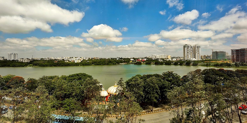 Nagavara lake with a tomb structure surrounded by greenery and distant buildings