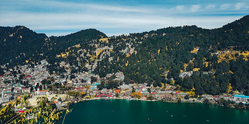 Nainital lake with a large water body surrounded by green mountains and buildings on hills