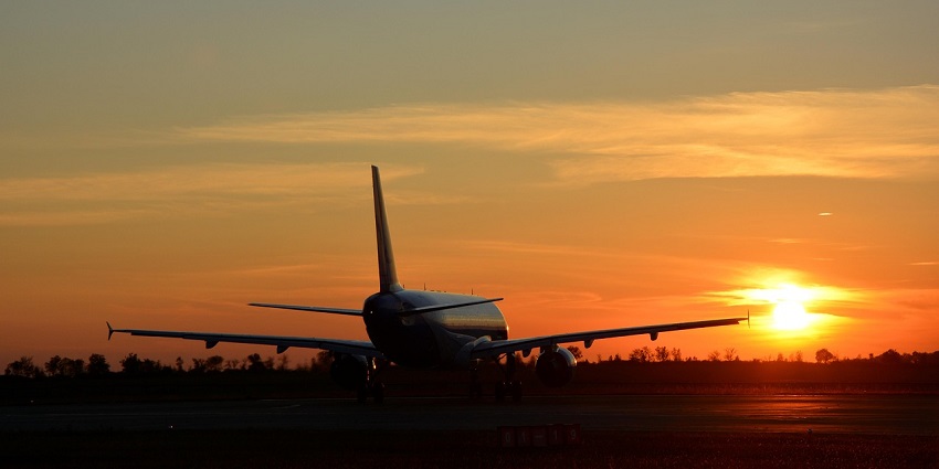 Aircraft parked at an airfield with the sunset painting the sky orange and colourful