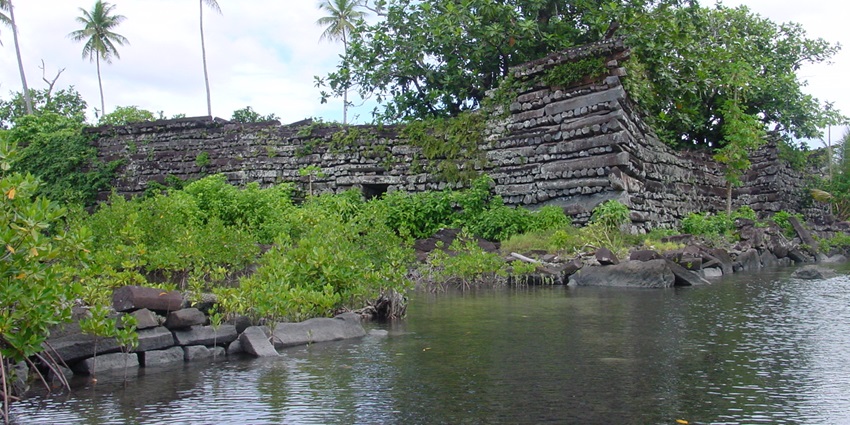 Ruins of Nan Madol in Pohnpei, Micronesia with lush greenery and a water body surrounding it.