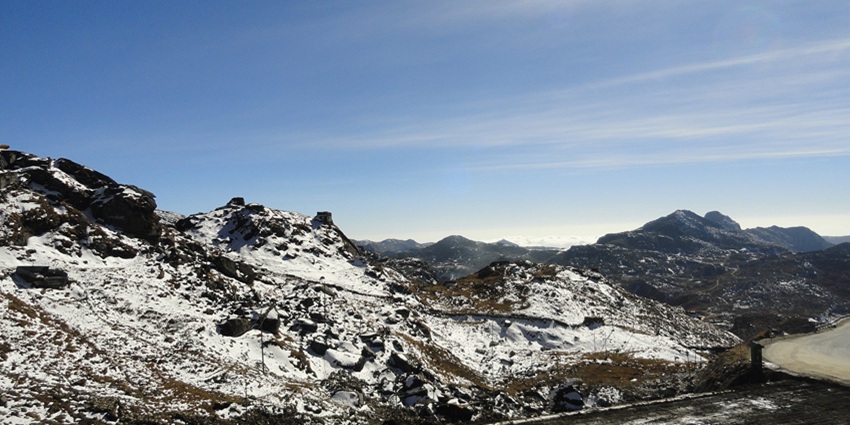 Nathula pass with a road on the right side and mountains that are partially covered in snow
