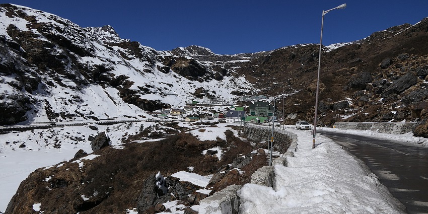 Nathula Pass with snow-covered area and clear road, street lights and a car passing by