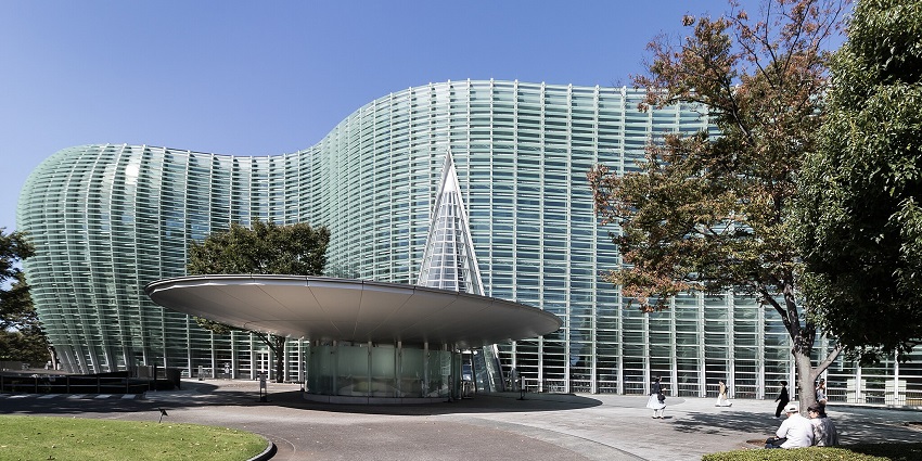 An image of a glass building of the National Art Centre, Tokyo, with a wavy design.