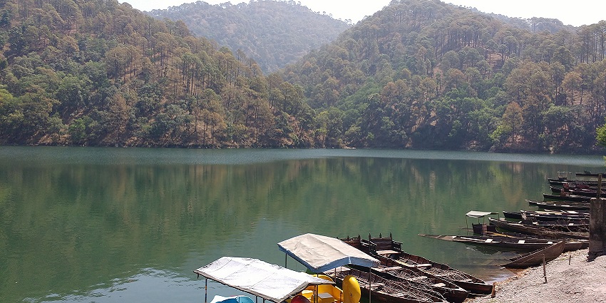 Naukuchiatal lake with multiple boats parked near the shore and reflecting greenery