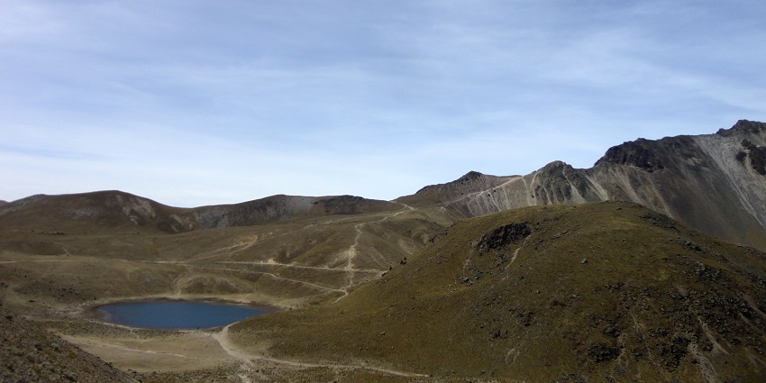 Nevado de Toluca with a small crater lake surrounded by sandy hills with narrow trails