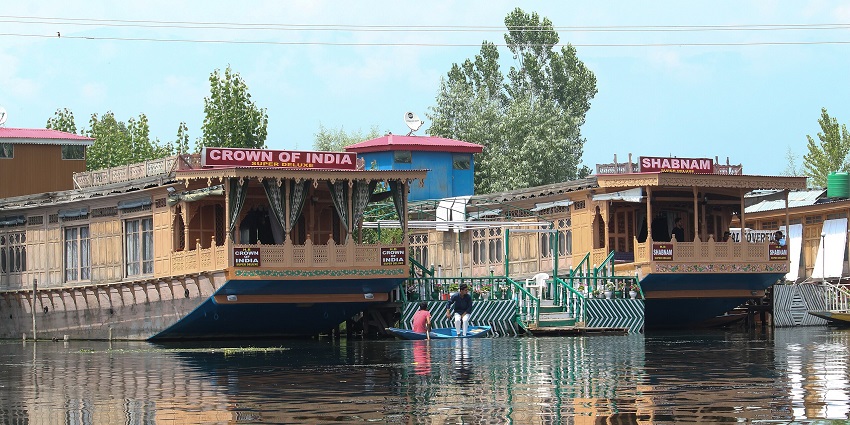 Couple of houseboats on a lake with a sign on the houseboat and multiple windows.