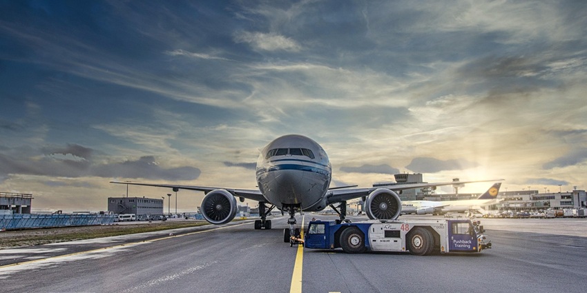 A white plane with small, dark windows on a grey and wet tarmac waiting to take off