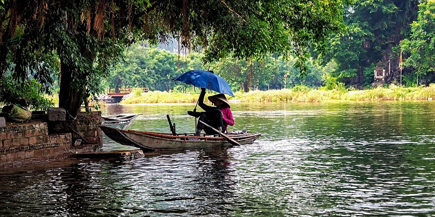 An image of the Ngo Dong River in Vietnam, surrounded by lush green karst mountains and calm waters