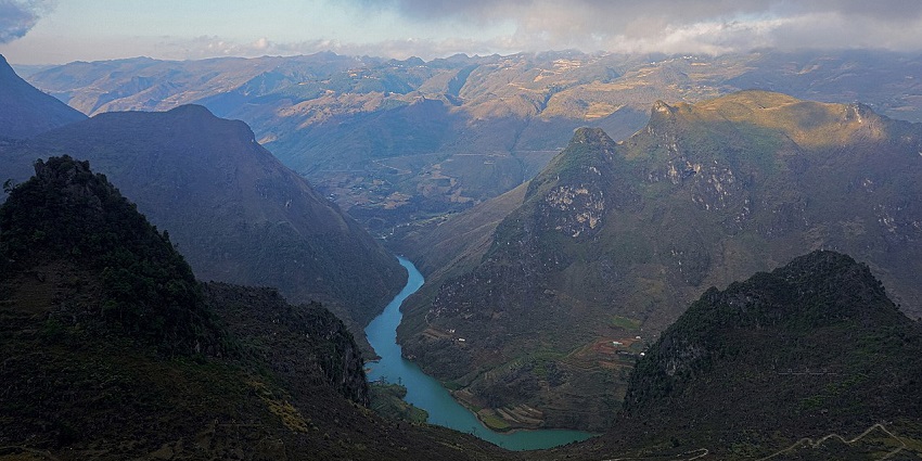 An image of the Nho Que River in Vietnam, with emerald waters flowing through steep, lush valleys