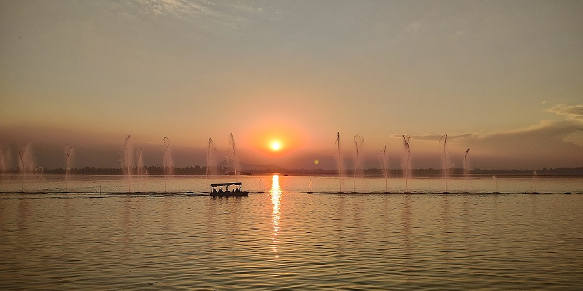 Nigeen lake in the evening with multiple people on a boat and passing by fountains