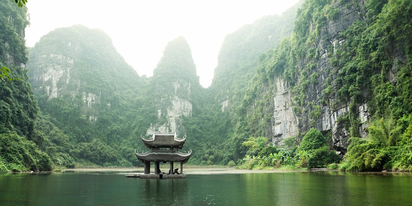A scenic view of the glistening emerald waters of Ninh Binh surrounded by lush greenery.