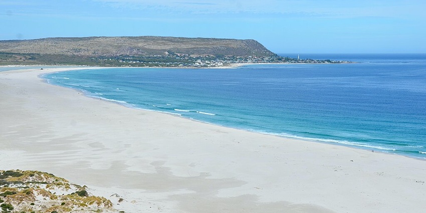 Nioumachoua Beach with sandy shorelines, a bright blue water body and distant green plains