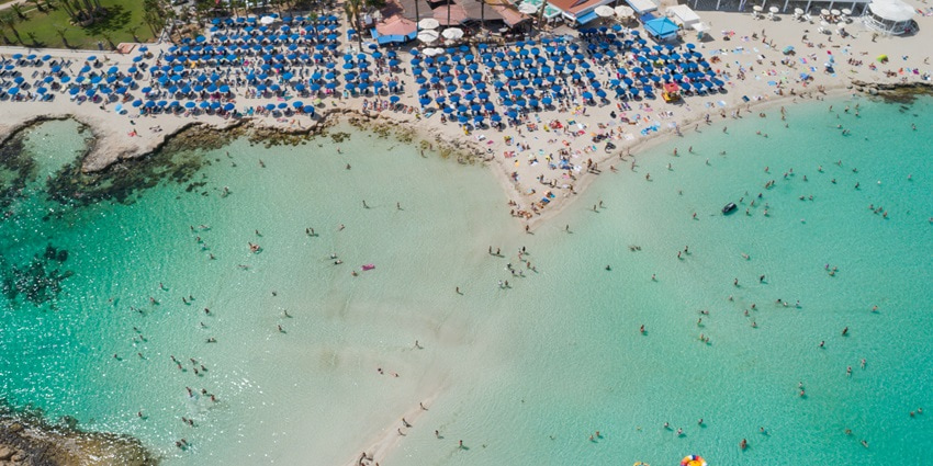 A lively beach with shallow turquoise waters, white sand, and a vibrant atmosphere