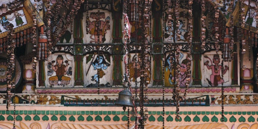 A temple facade with colourful Hindu deities painted on panels and hanging decorations.