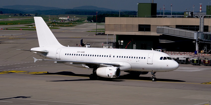An aeroplane takes off, and blue silhouettes of hills and green forests appear in the distance.
