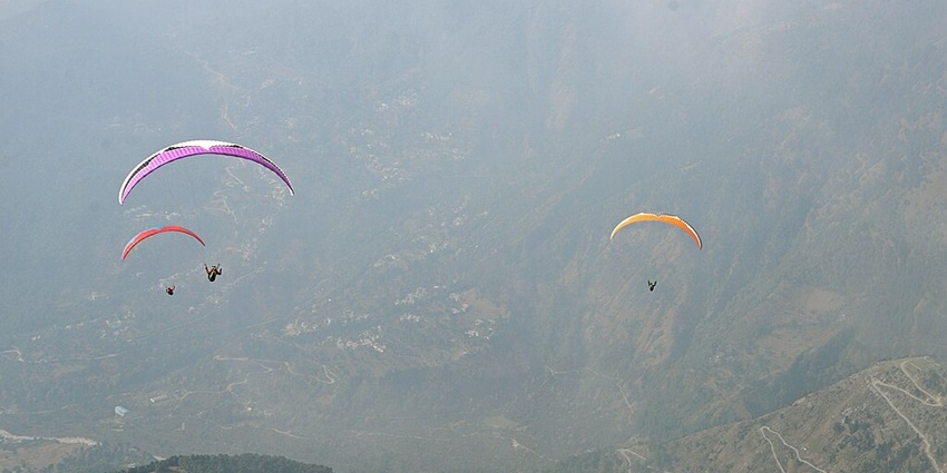 An image of paragliders in colourful canopies in Bir Billing, the highest paragliding in India.