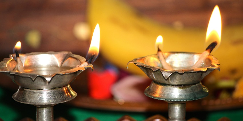 Two brass oil lamps with burning cotton lines dipped in oil and a banana in the back