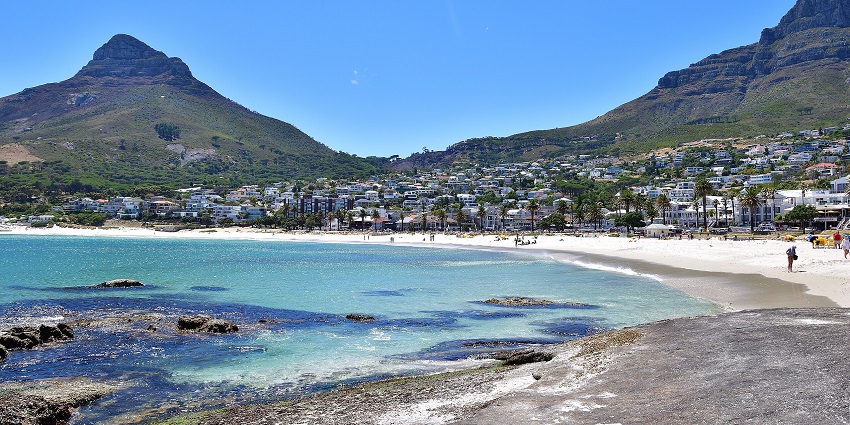 An image of a beautiful coastal town at Camps Bay Beach with palm trees all around.