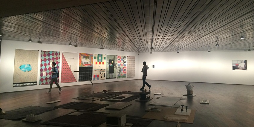 View of a paintings hung on the wall of the museum, with tourists wandering around