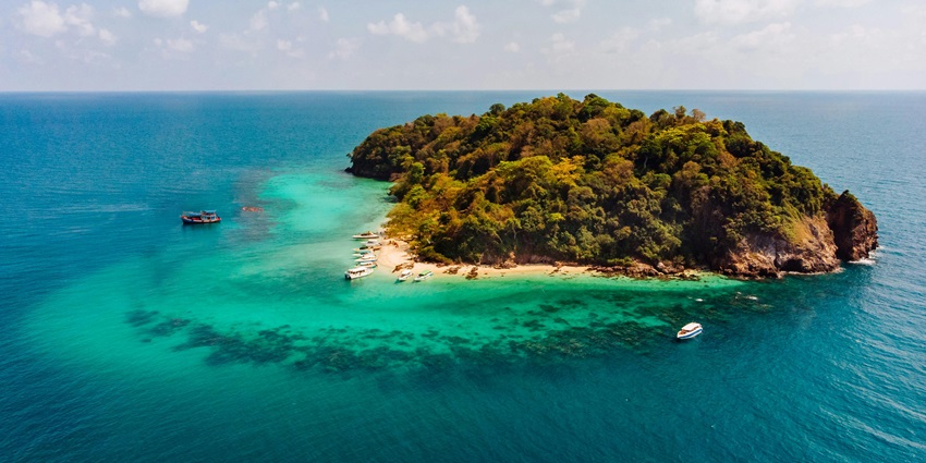 Aerial view of an Trobriand island surrounded by water, displaying its land features.
