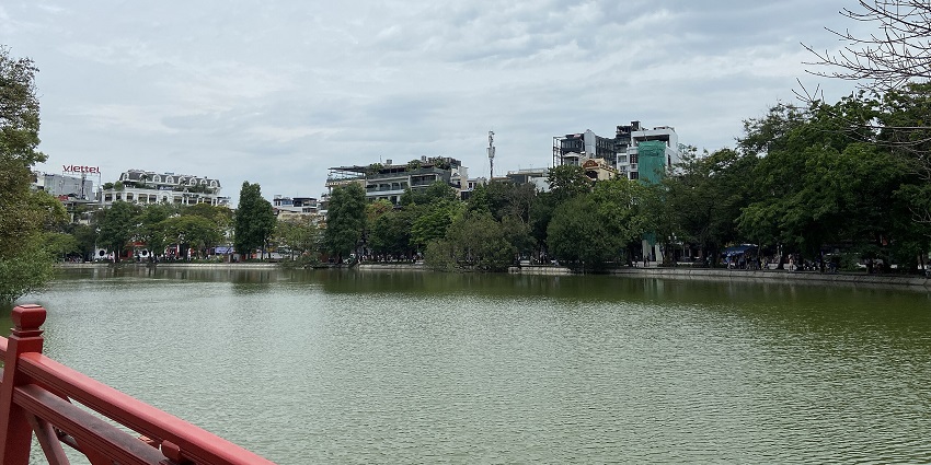 A tourist sitting by Hoàn Kiếm Lake, enjoying the peaceful atmosphere