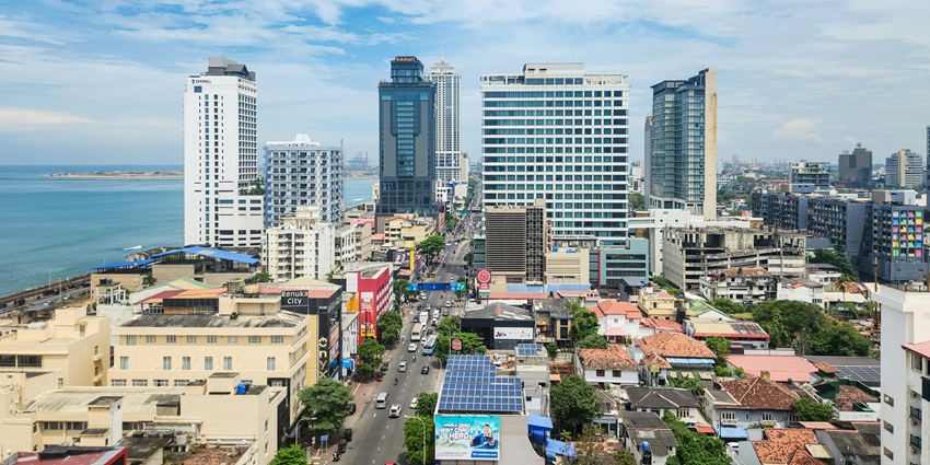 An image of Sri Lanka city skyline, arches, manicured lawns, a pathway, and cloudy skies