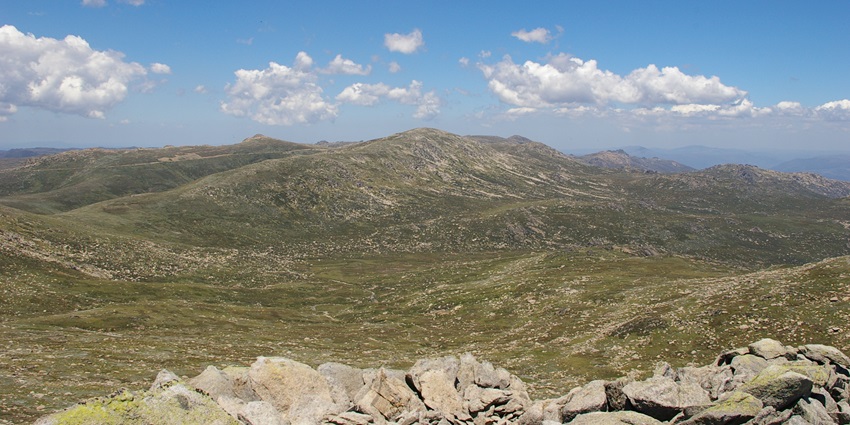 Panoramic view of Mount Kosciuszko with trails and blue skies.
