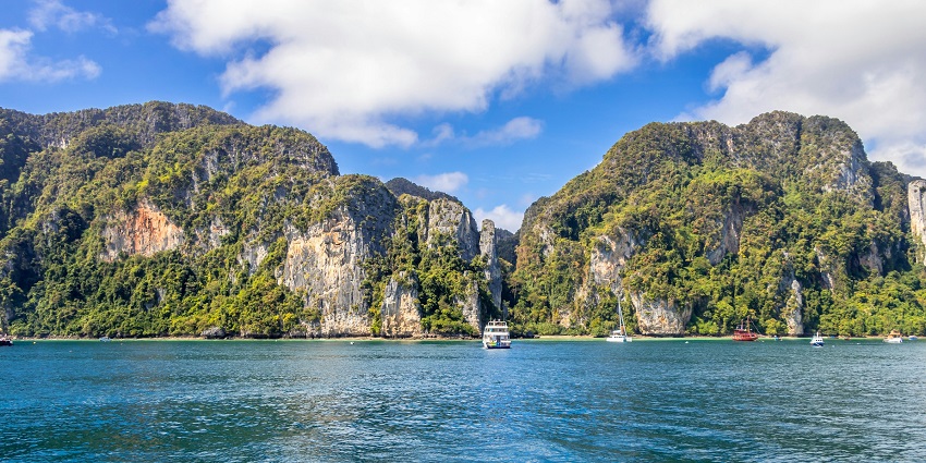 View of serene shores of Krabi, covered by lush trees and the clear blue sky in the background