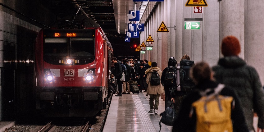 Travellers waiting in a train station wearing winter clothes like jackets and caps