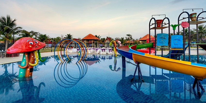 A water park with a swimming pool, a colorful mushroom-shaped fountain, and slides