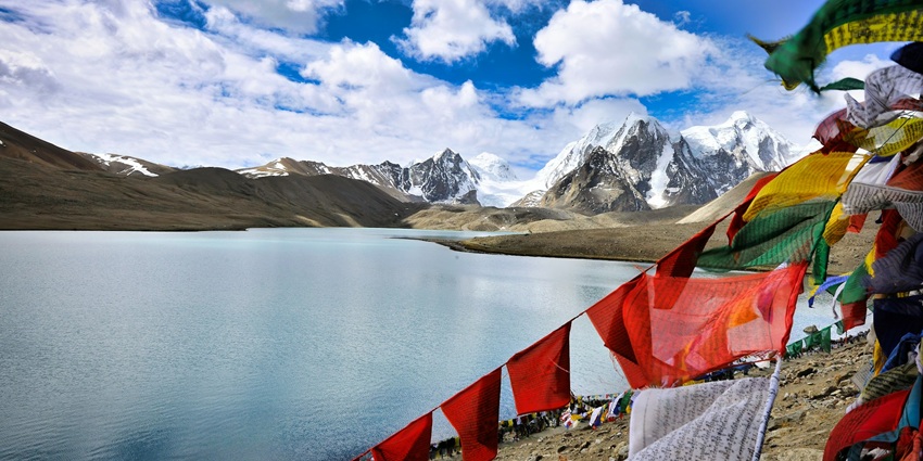 Image of Gurudongmar lake in May with picturesque views and buddhist flags displayed