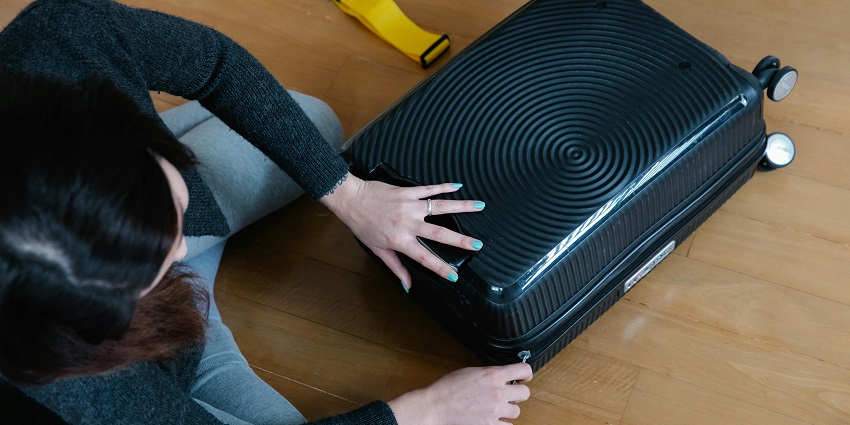 Image of a woman packing her black travelling bag for travelling Georgia
