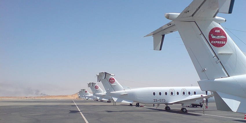 Aeroplanes parked at runway of Oued Irara-Krim Belkacem Airport and distant sandy plains
