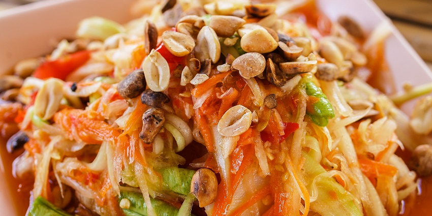 Spicy papaya salad with shredded vegetables, crunchy peanuts, and a tangy dressing.