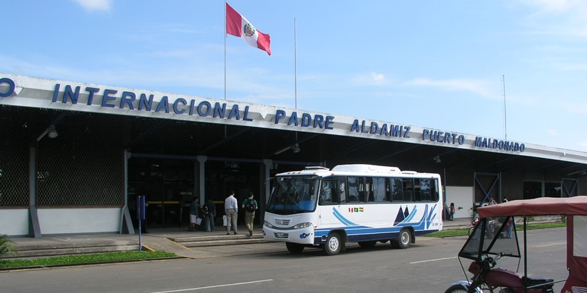 Padre Aldamiz International Airport, one of the airports in Peru, with the Peru flag waving on top, a bus in front, and people at the entrance