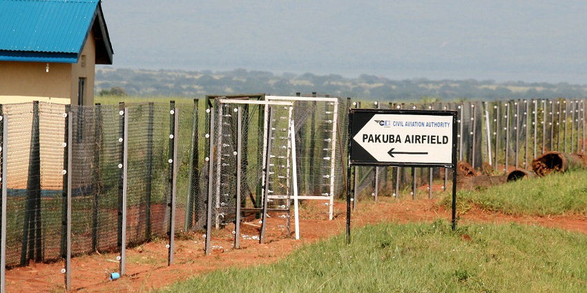 Pakuba airport, one of the airports in Uganda, with a small blue roof hut, steel net fences and a signboard of Pakuba Airfield